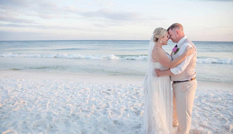 couple s'embrasse sur la plage portant des vêtements de mariage